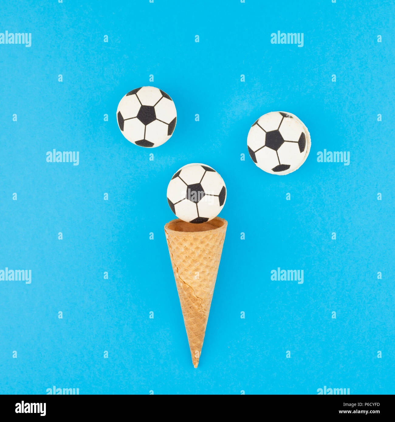 Square télévision créative jeter Vue de dessus de la crème glacée cônes alvéolés avec des ballons de foot macarons sur fond bleu clair bold avec copie espace dans un style minimaliste Banque D'Images