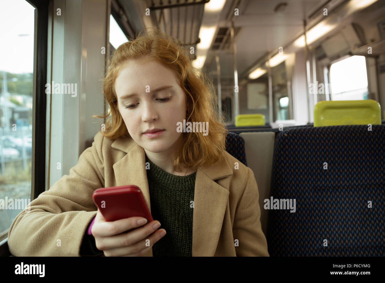 Cheveux rouge jeune femme en utilisant son mobile Banque D'Images