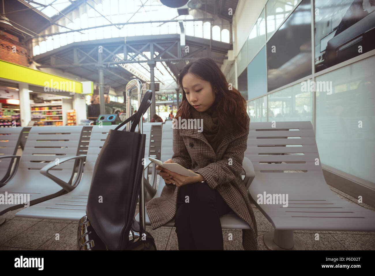 Femme à l'aide de téléphone mobile en zone d'attente Banque D'Images