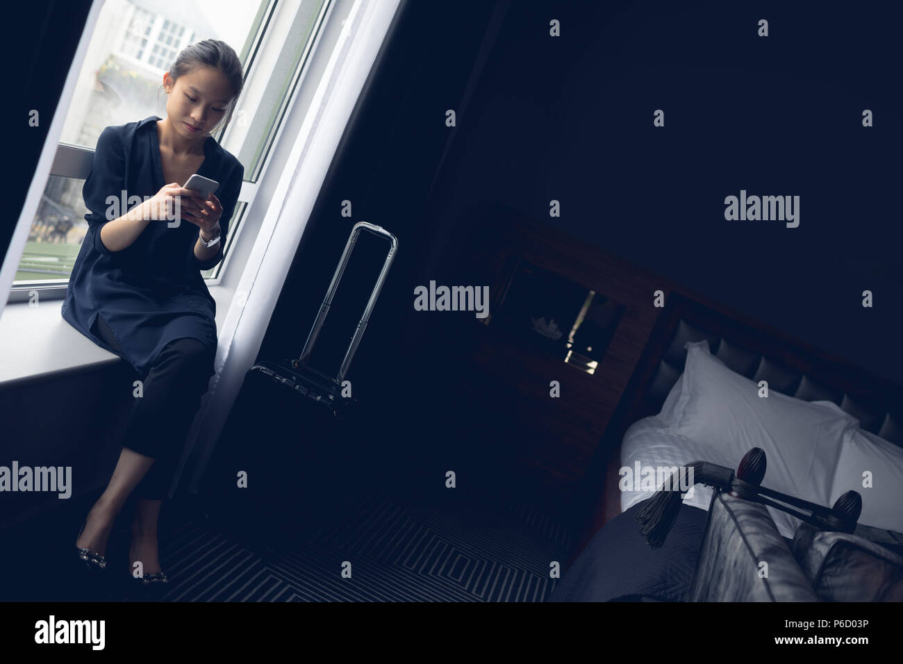 Woman using mobile phone in hotel room Banque D'Images