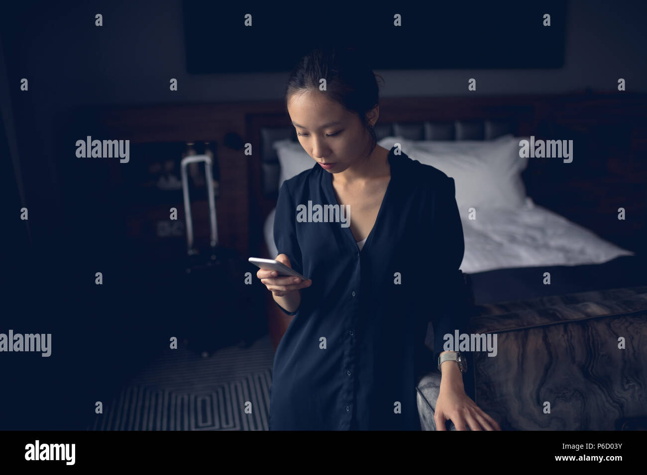 Woman using mobile phone in hotel room Banque D'Images