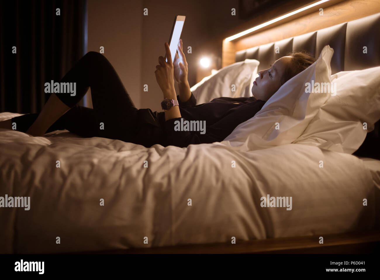 Woman using digital tablet while relaxing on bed Banque D'Images