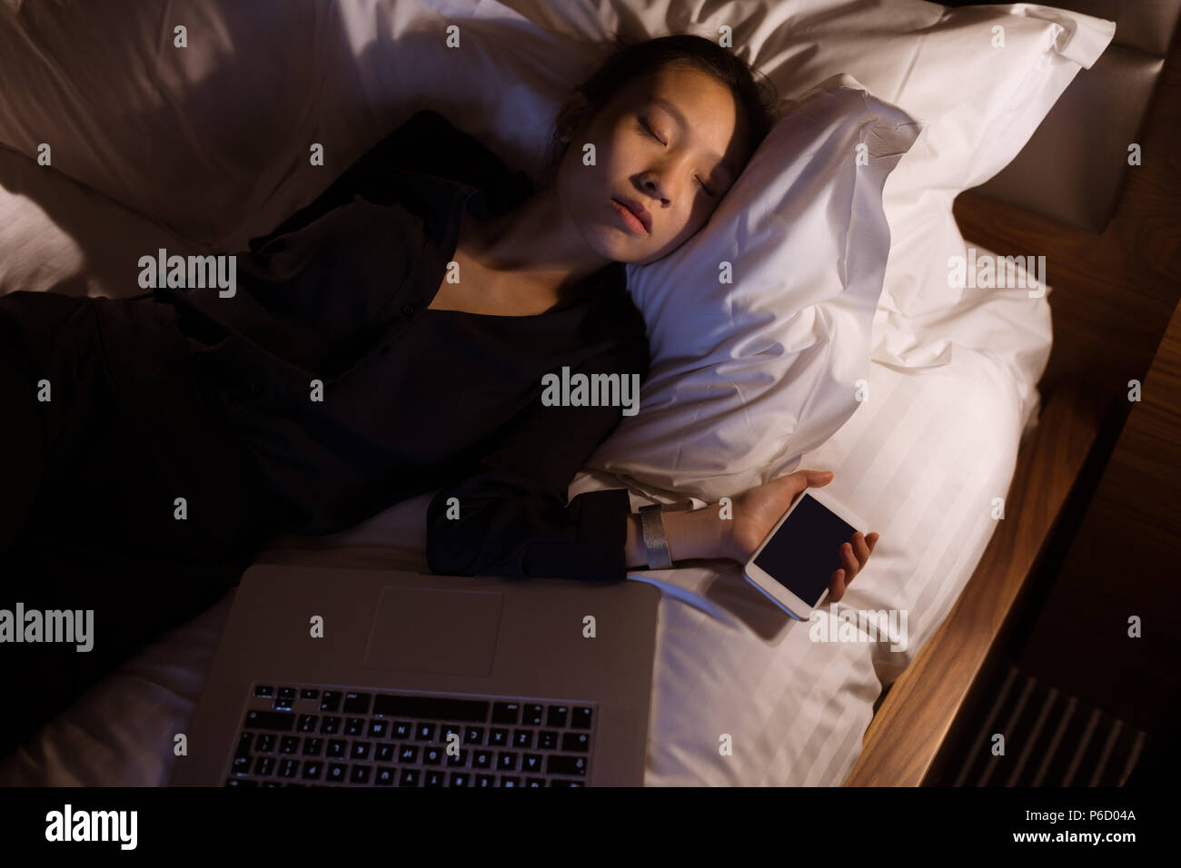 Tired woman sleeping avec ordinateur portable et mobile pone on bed Banque D'Images