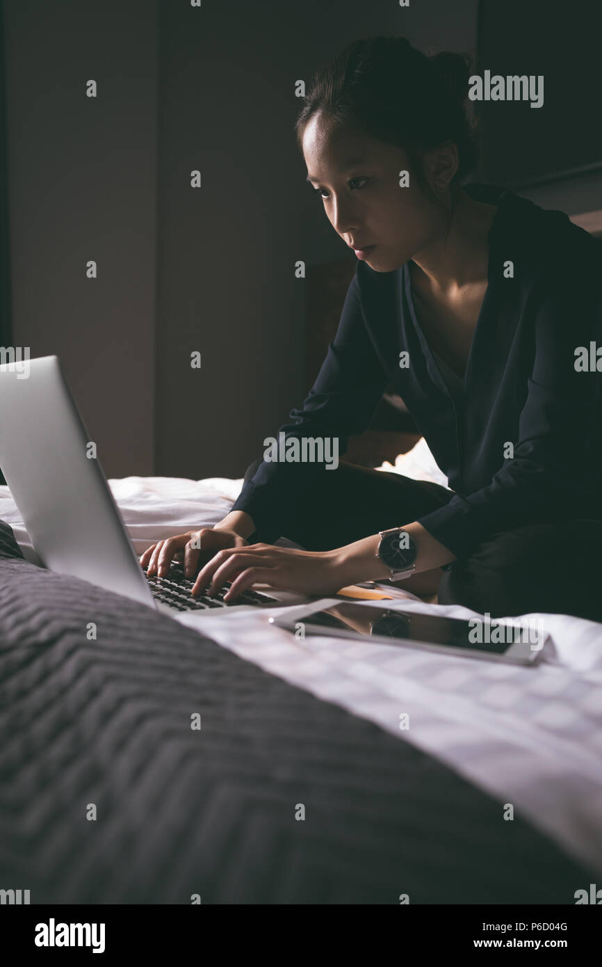 Belle femme à l'aide de téléphone mobile tout en vous relaxant sur le lit Banque D'Images