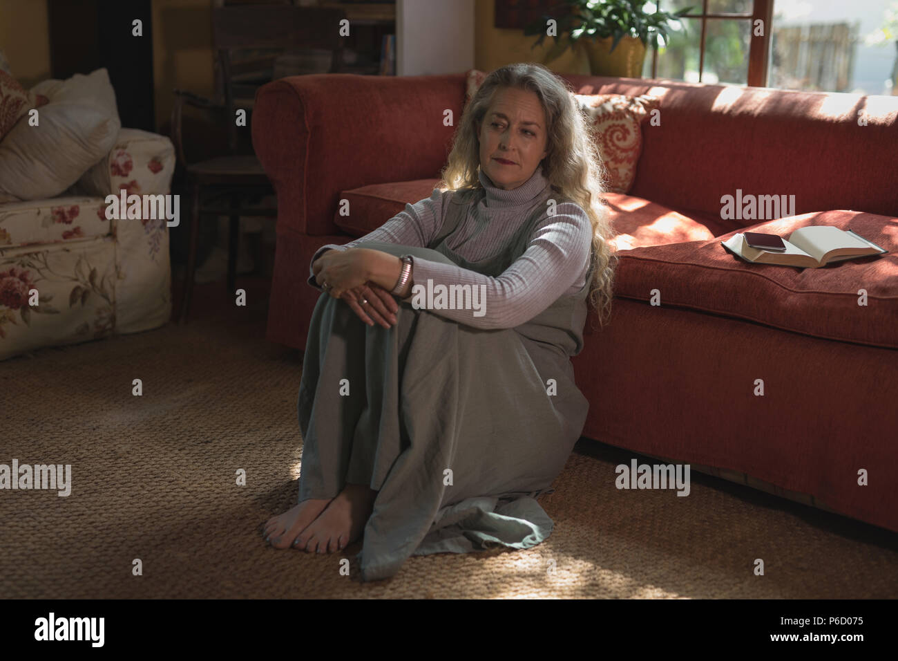 Thoughtful mature woman sitting on ground Banque D'Images