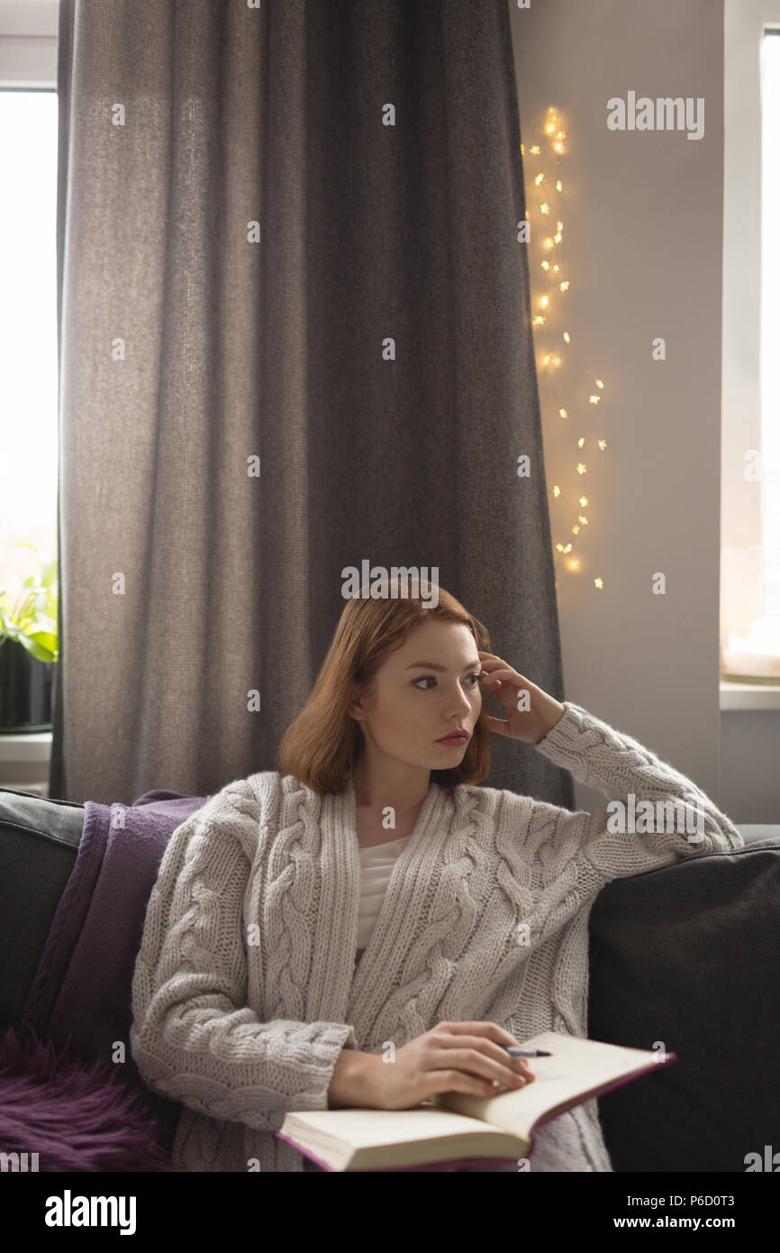 Femme écrivant sur un journal dans la salle de séjour à la maison Banque D'Images