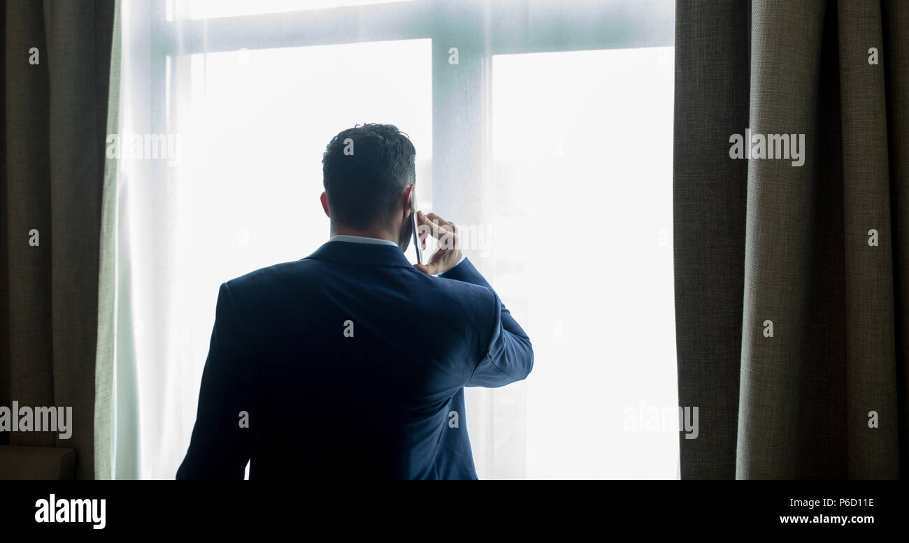 Businessman talking on mobile phone in hotel room Banque D'Images