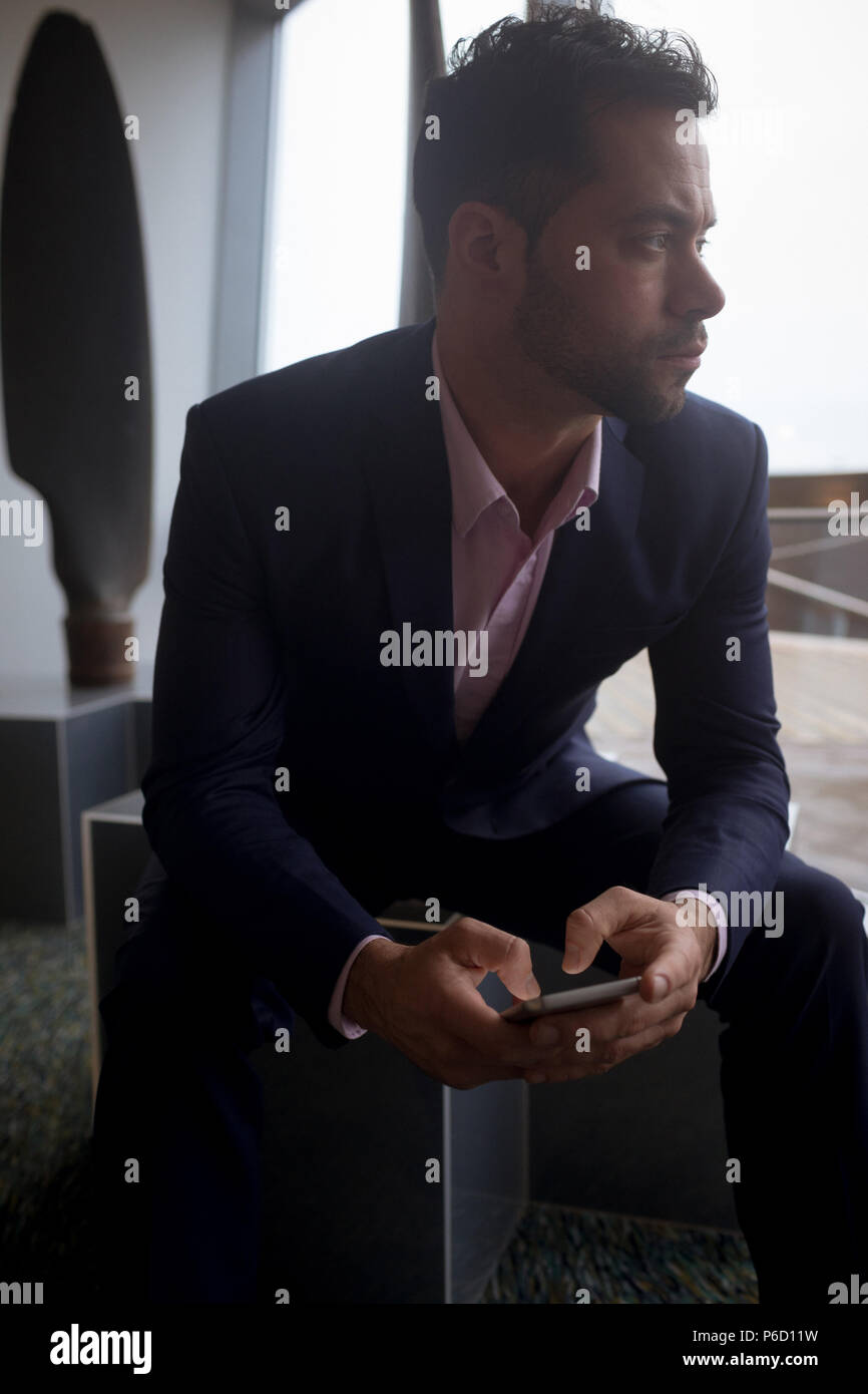 Businessman using mobile phone in hotel room Banque D'Images