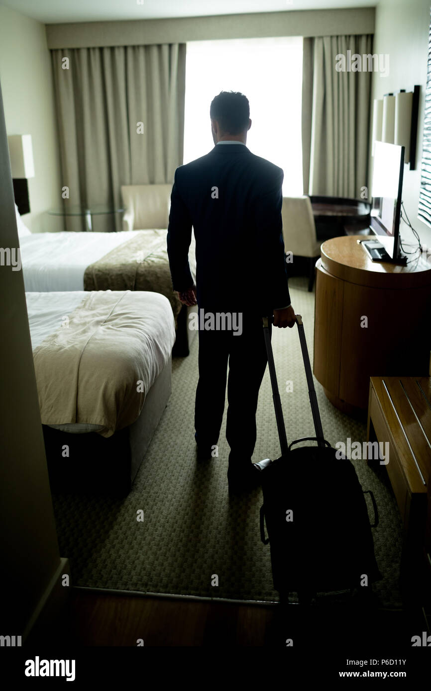 Businessman standing with luggage in hotel room Banque D'Images