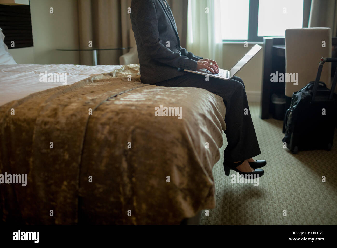 Businesswoman using laptop on bed Banque D'Images