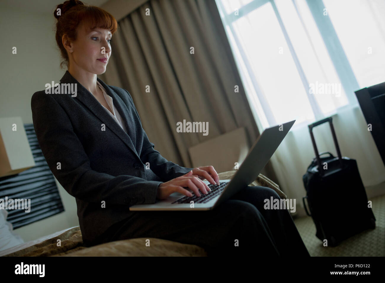 Businesswoman using laptop on bed Banque D'Images