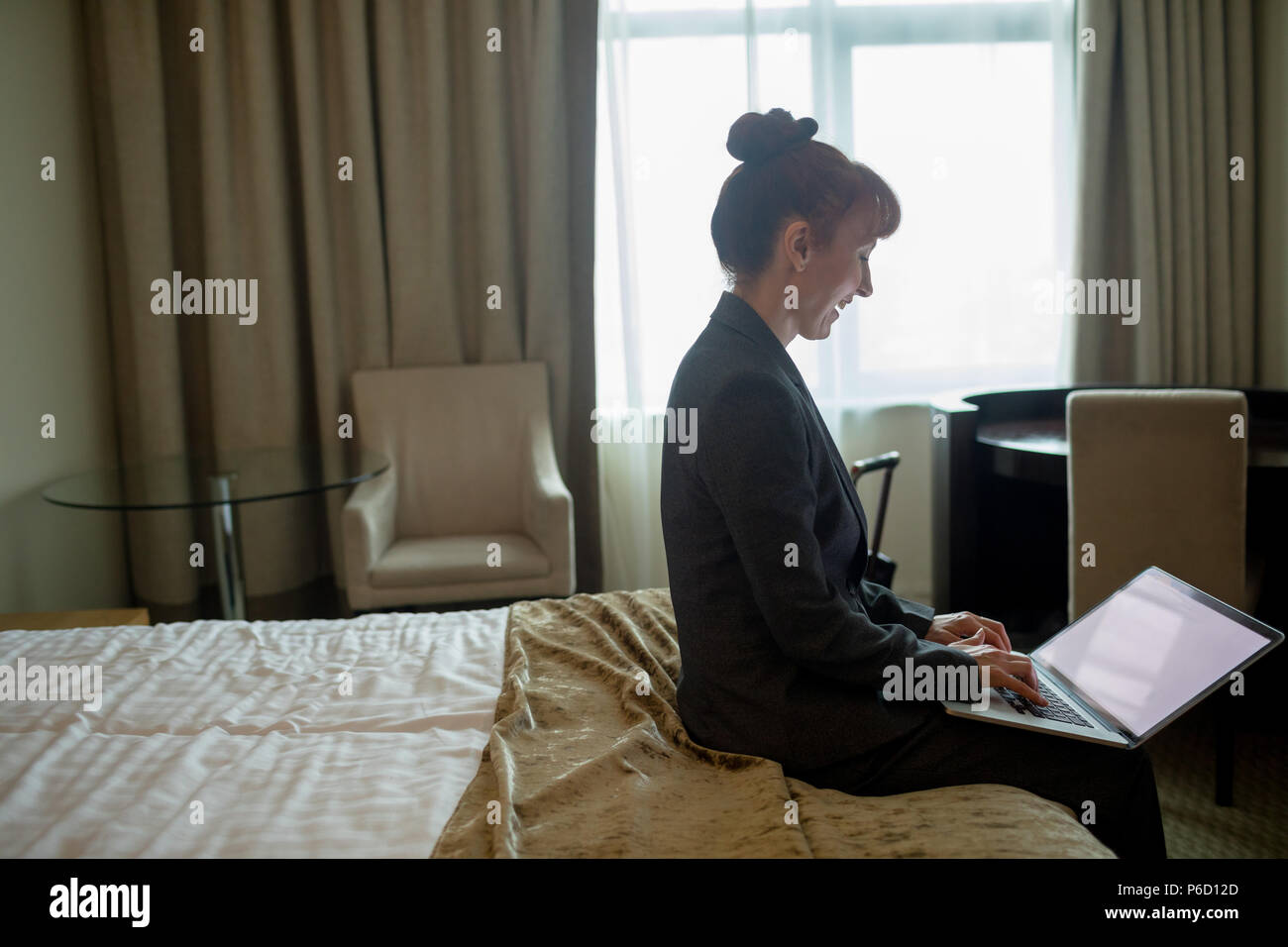 Businesswoman using laptop on bed Banque D'Images