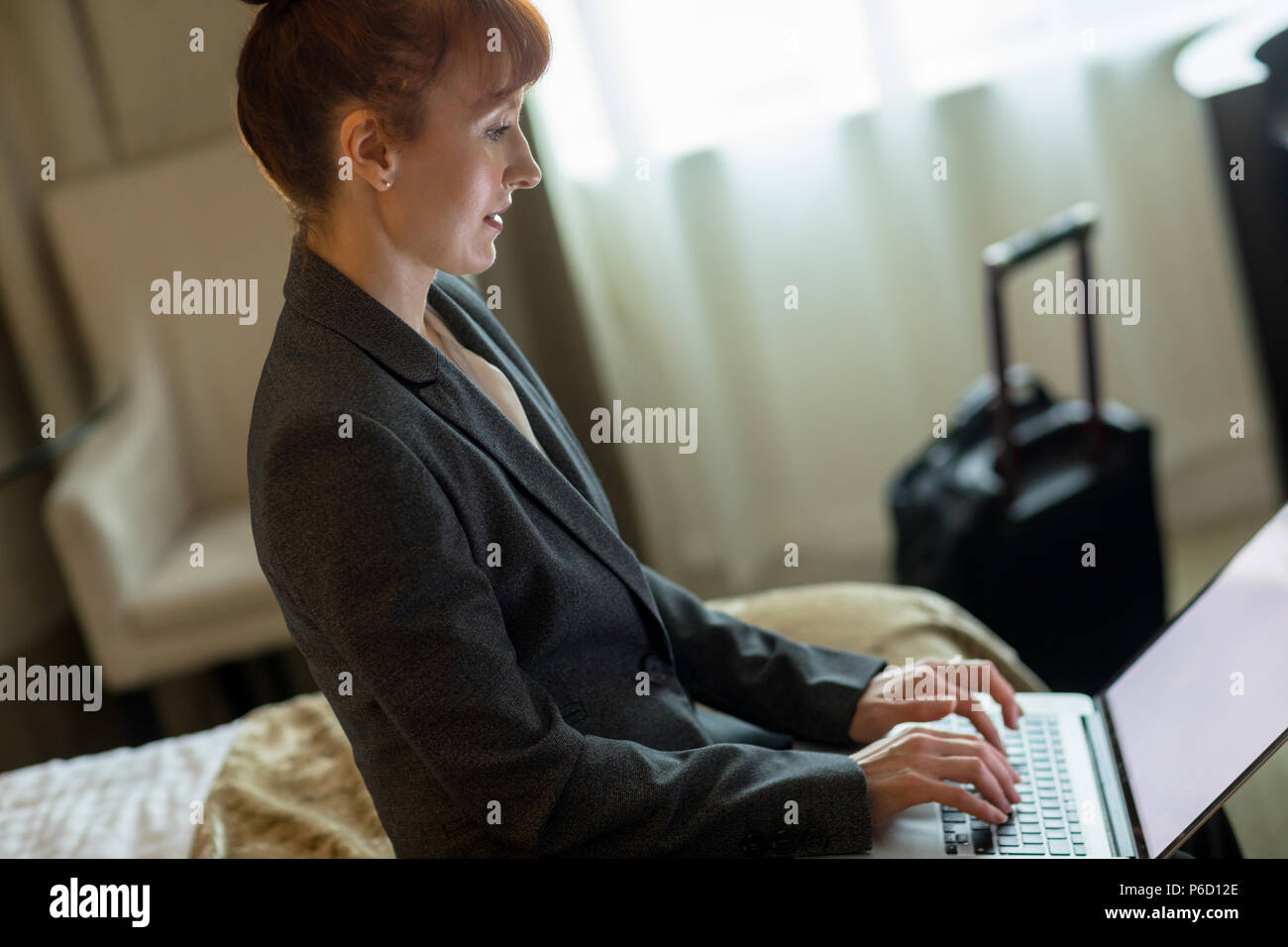 Businesswoman using laptop on bed Banque D'Images