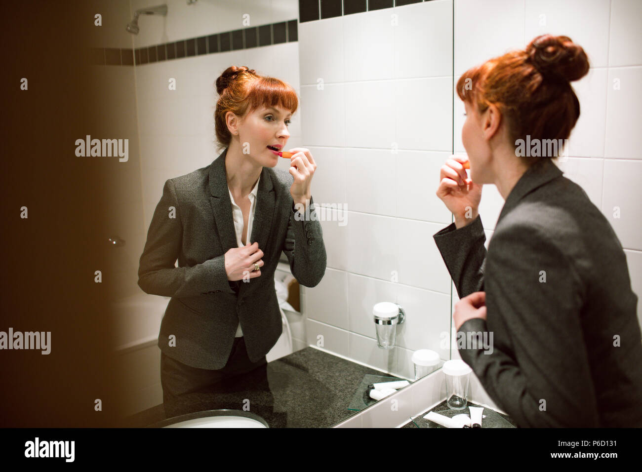 Woman applying lipstick dans la salle de bains Banque D'Images