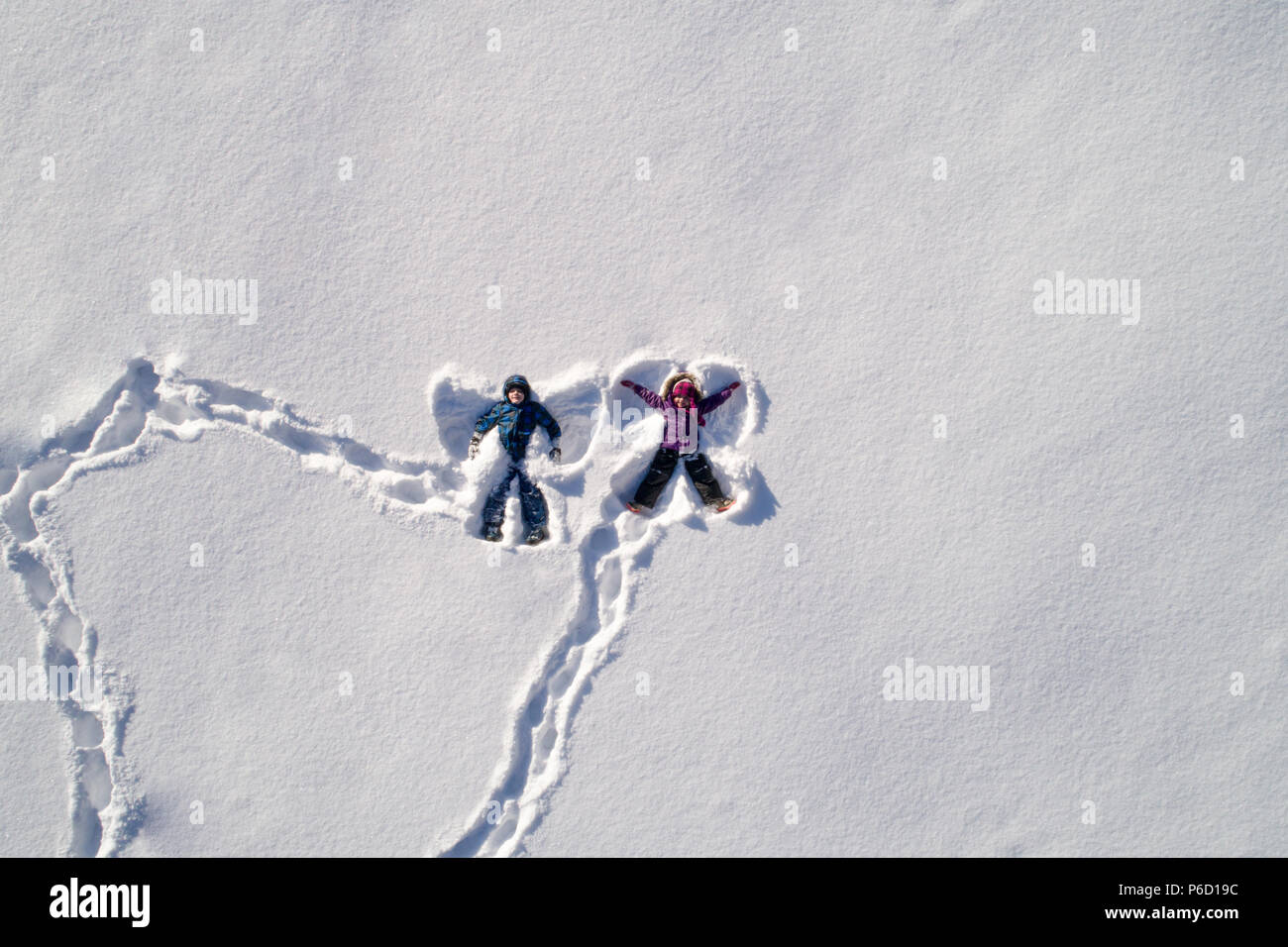 Les enfants se trouvant sur la neige et la neige qui forme l'ange Banque D'Images