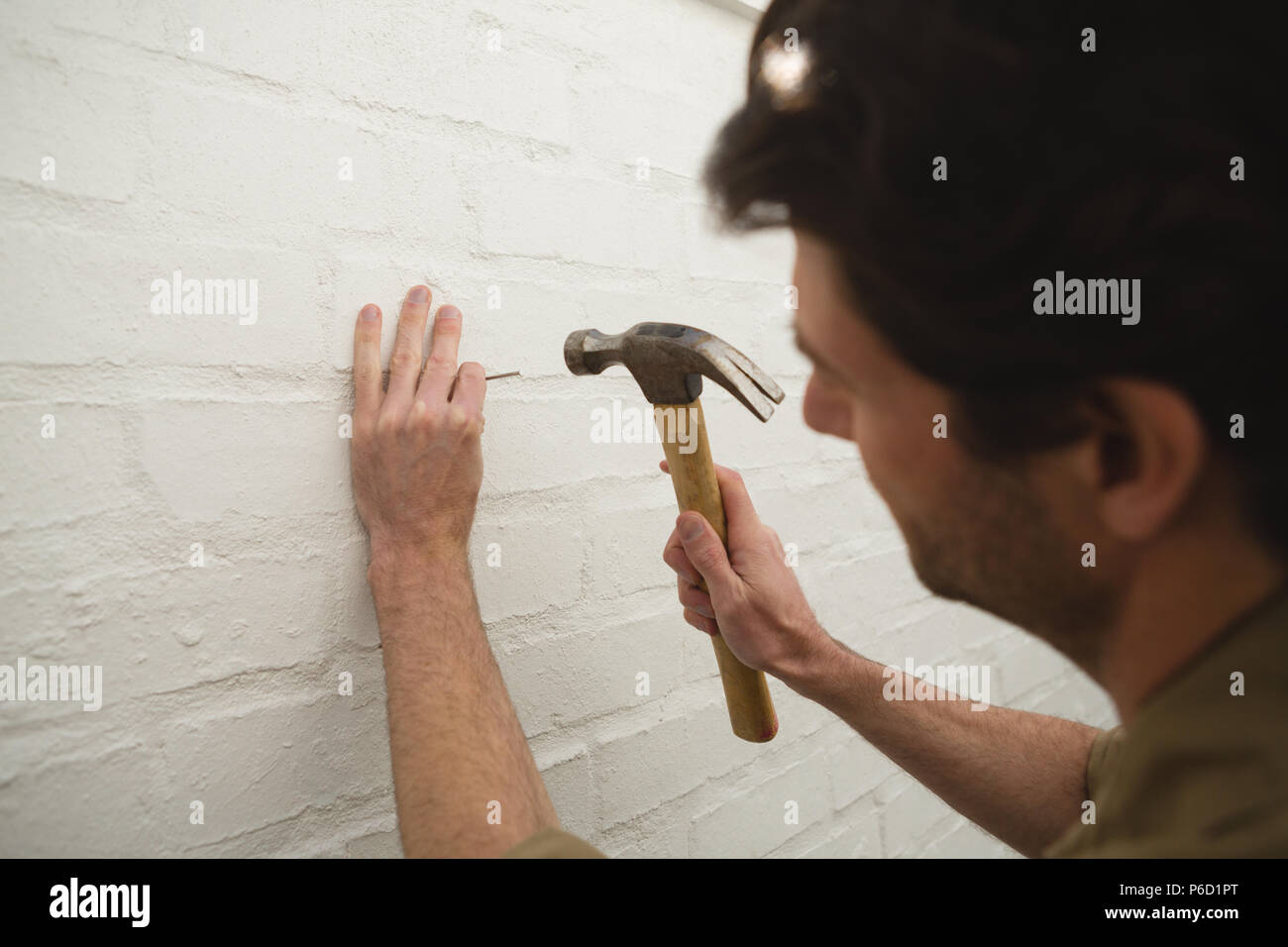 Male carpenter hammering nail on wall Banque D'Images