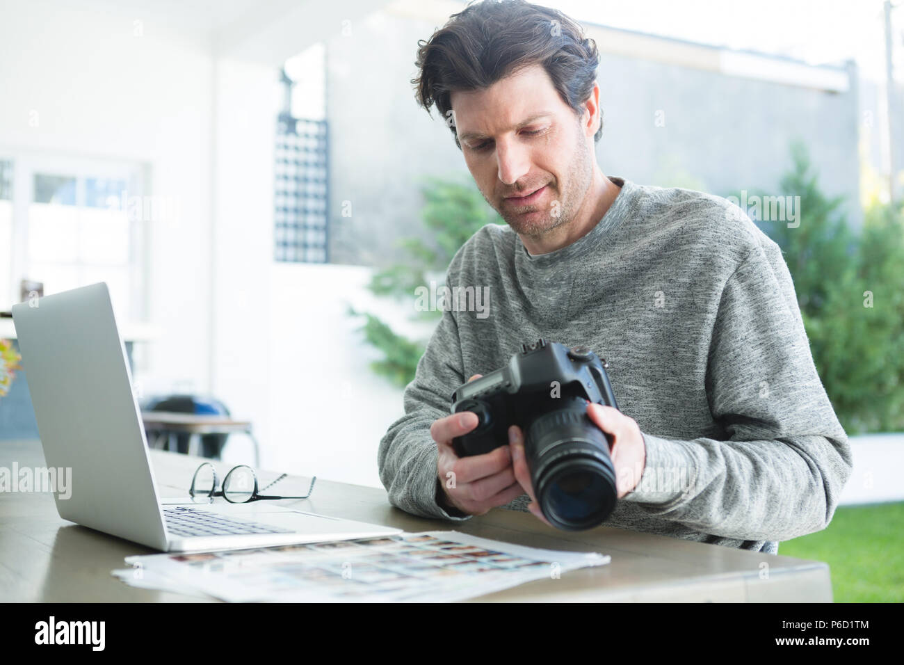 Man using laptop and holding digital camera Banque D'Images