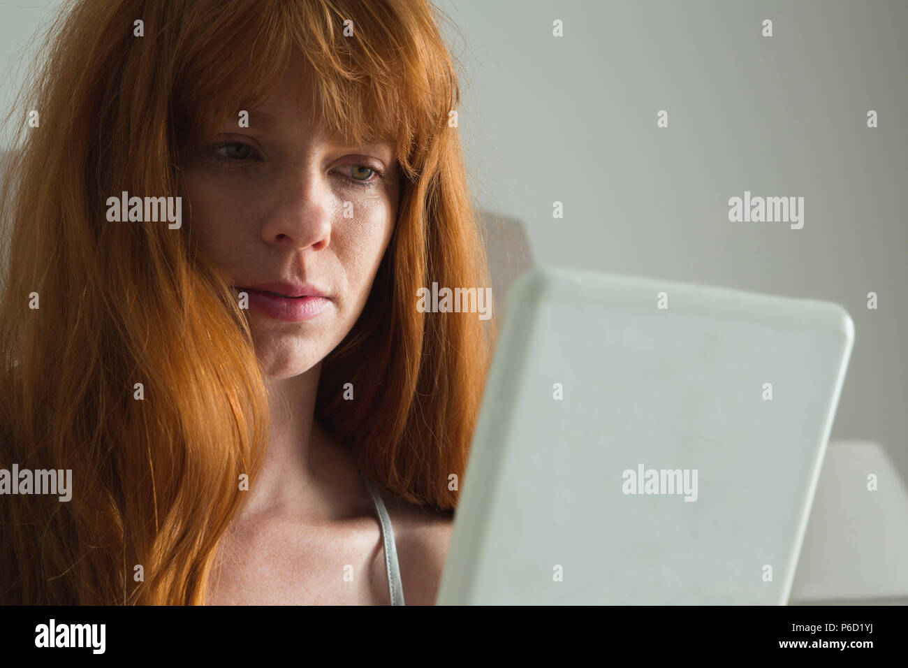 Woman using digital tablet in bedroom Banque D'Images