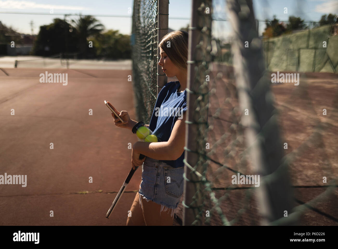 Femme à l'aide de téléphone mobile dans la cour de tennis Banque D'Images