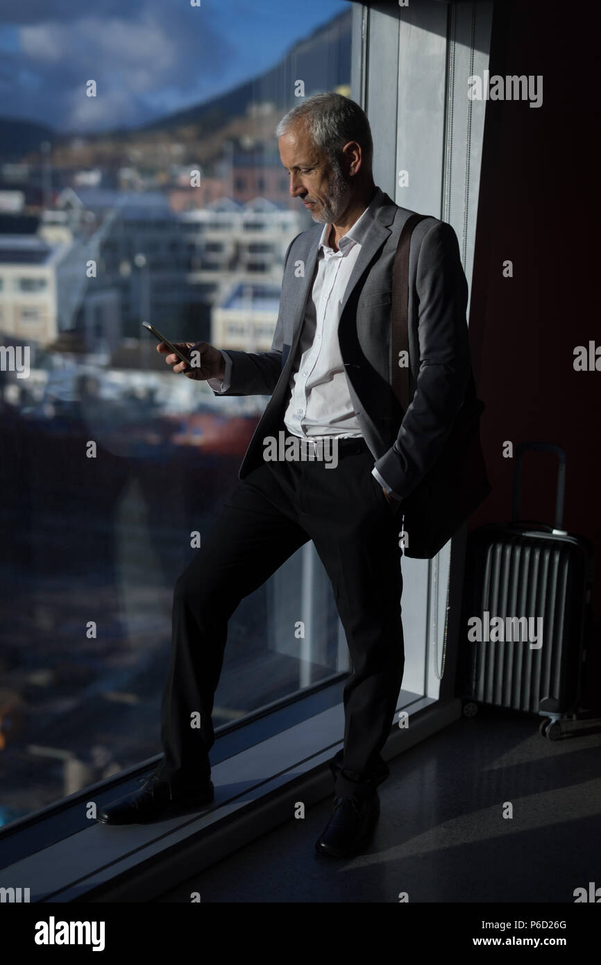 Businessman using mobile phone in hotel room Banque D'Images