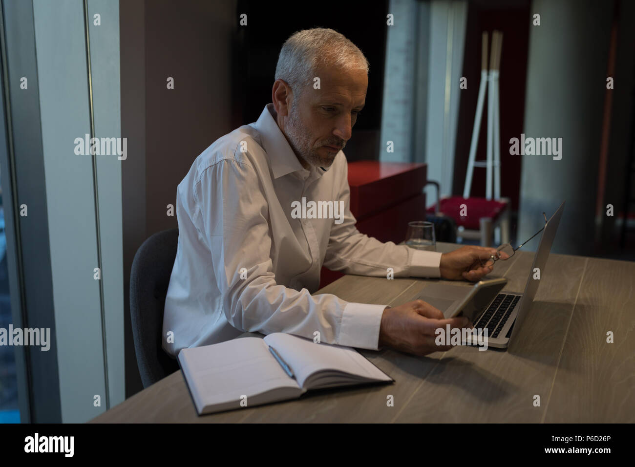 Businessman using mobile phone while working on laptop Banque D'Images