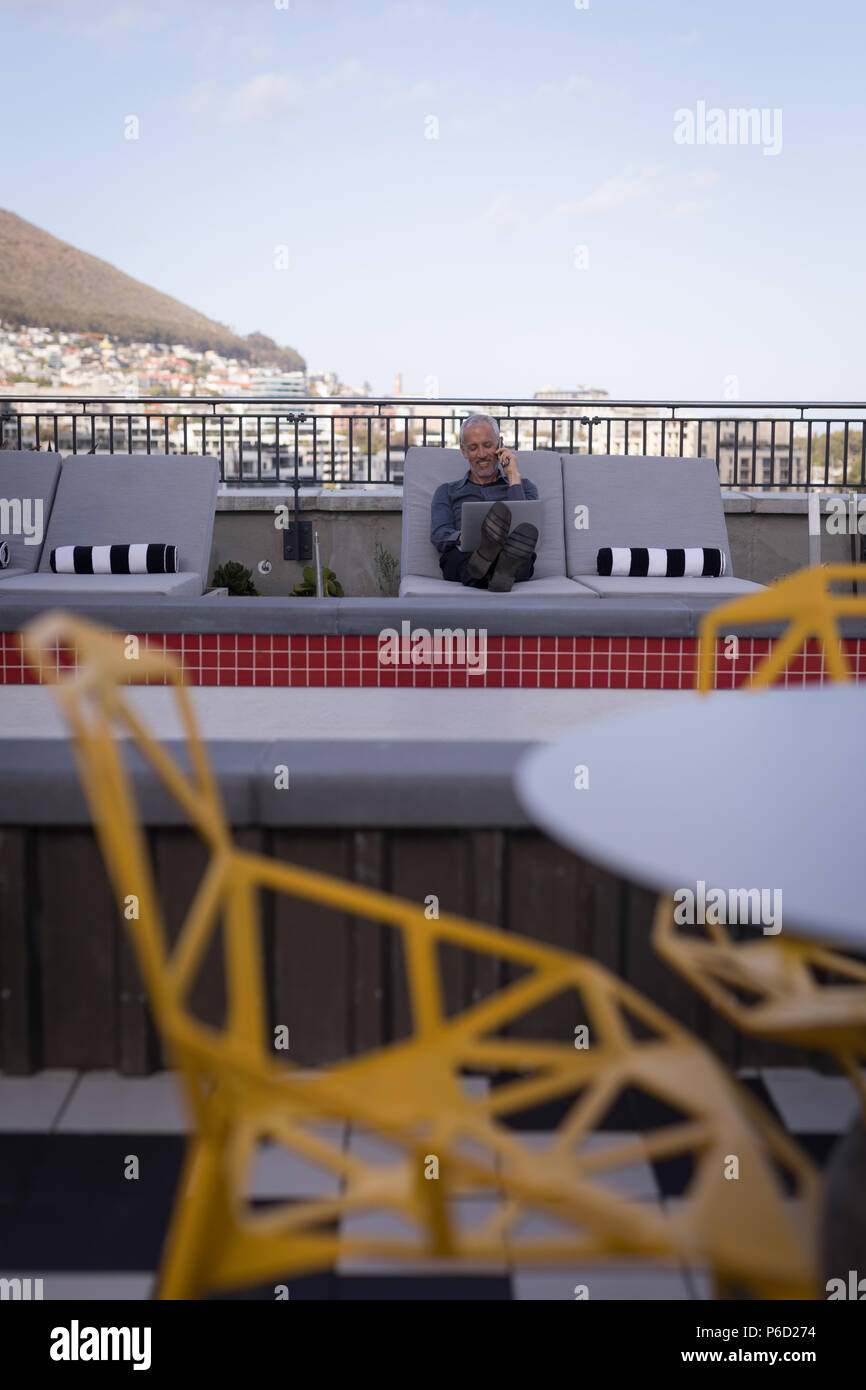 Businessman talking on mobile phone while working on laptop Banque D'Images