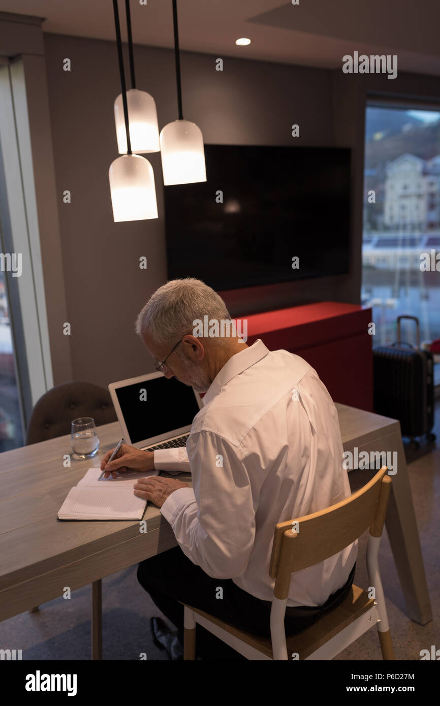 Businessman taking notes sur un ordinateur portable Banque D'Images