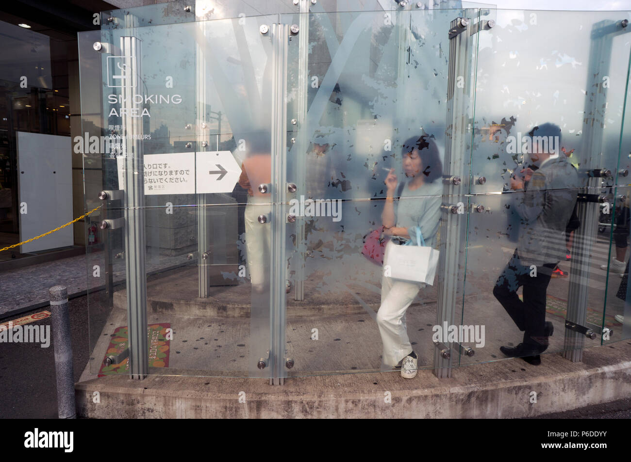 Les fumeurs à l'extérieur de public Shinamomachi la gare, Tokyo, Japon Banque D'Images