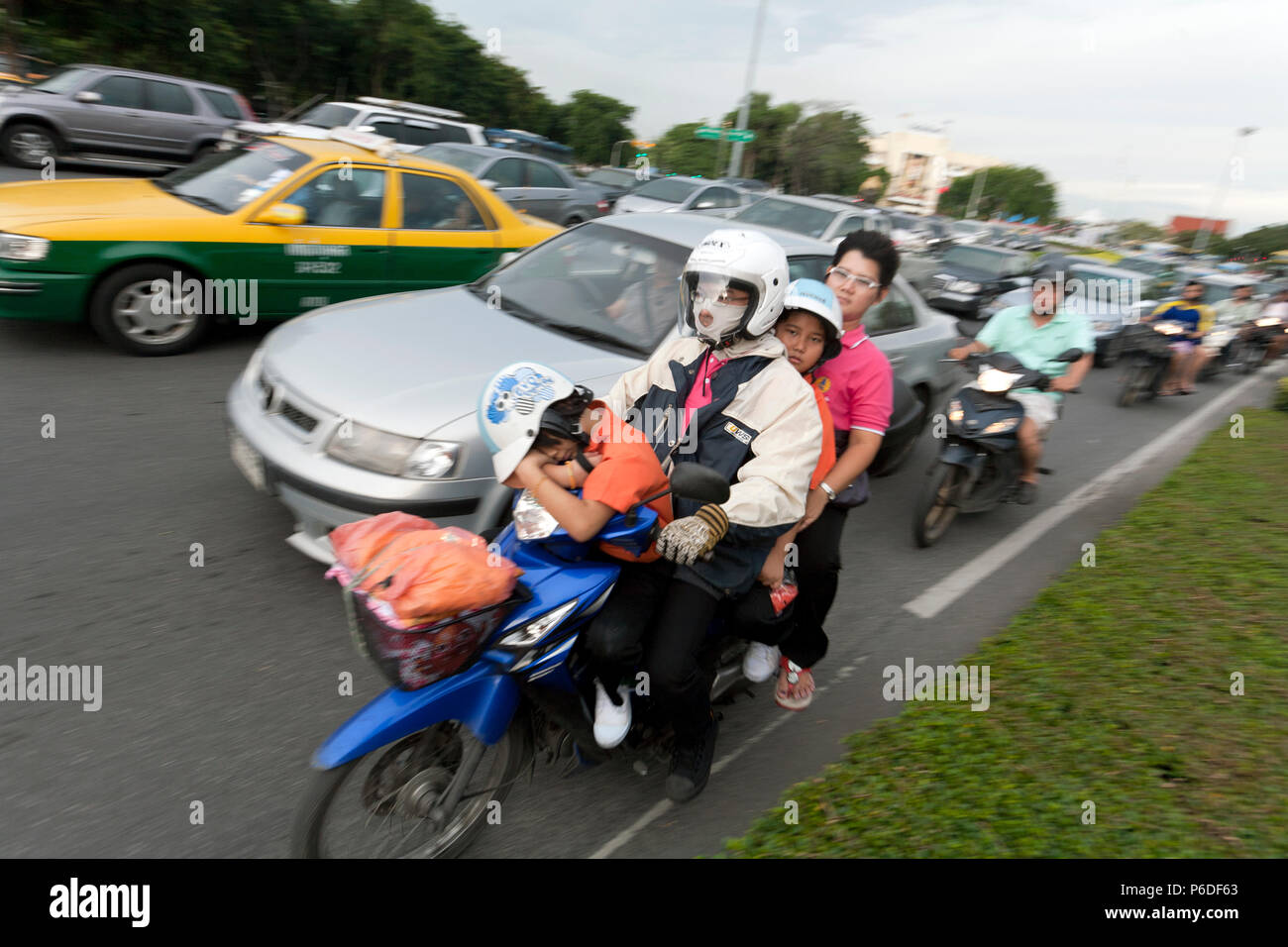 Femme transportant trois enfants sur son cyclomoteur dans Bangkok, Thaïlande le trafic congestionné Banque D'Images