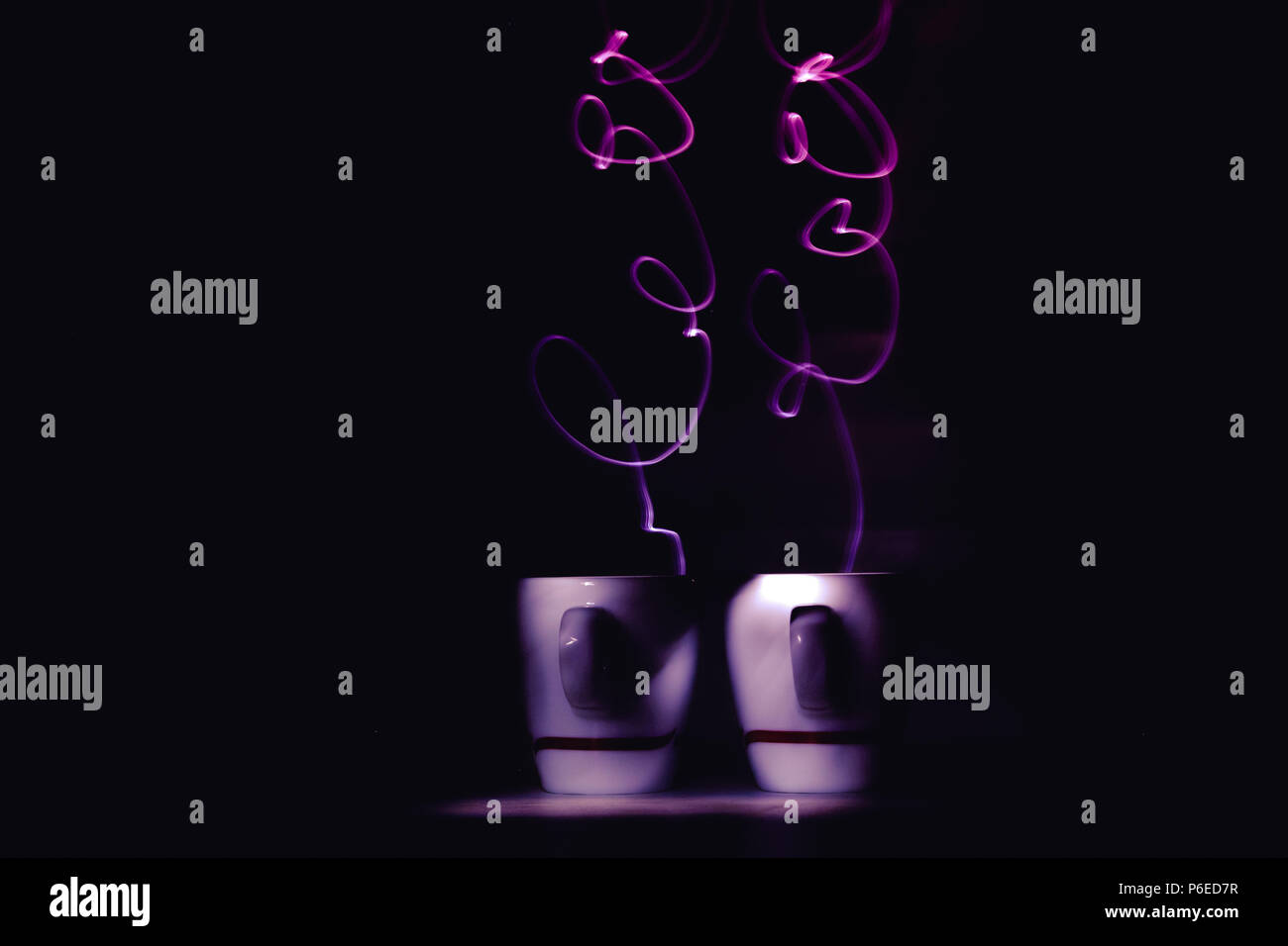 Pinceau de lumière, lightgraphy ou lightpainting de couleur violette de vapeur mot amour de petites tasses à expresso café - art photography. Copyspace Banque D'Images