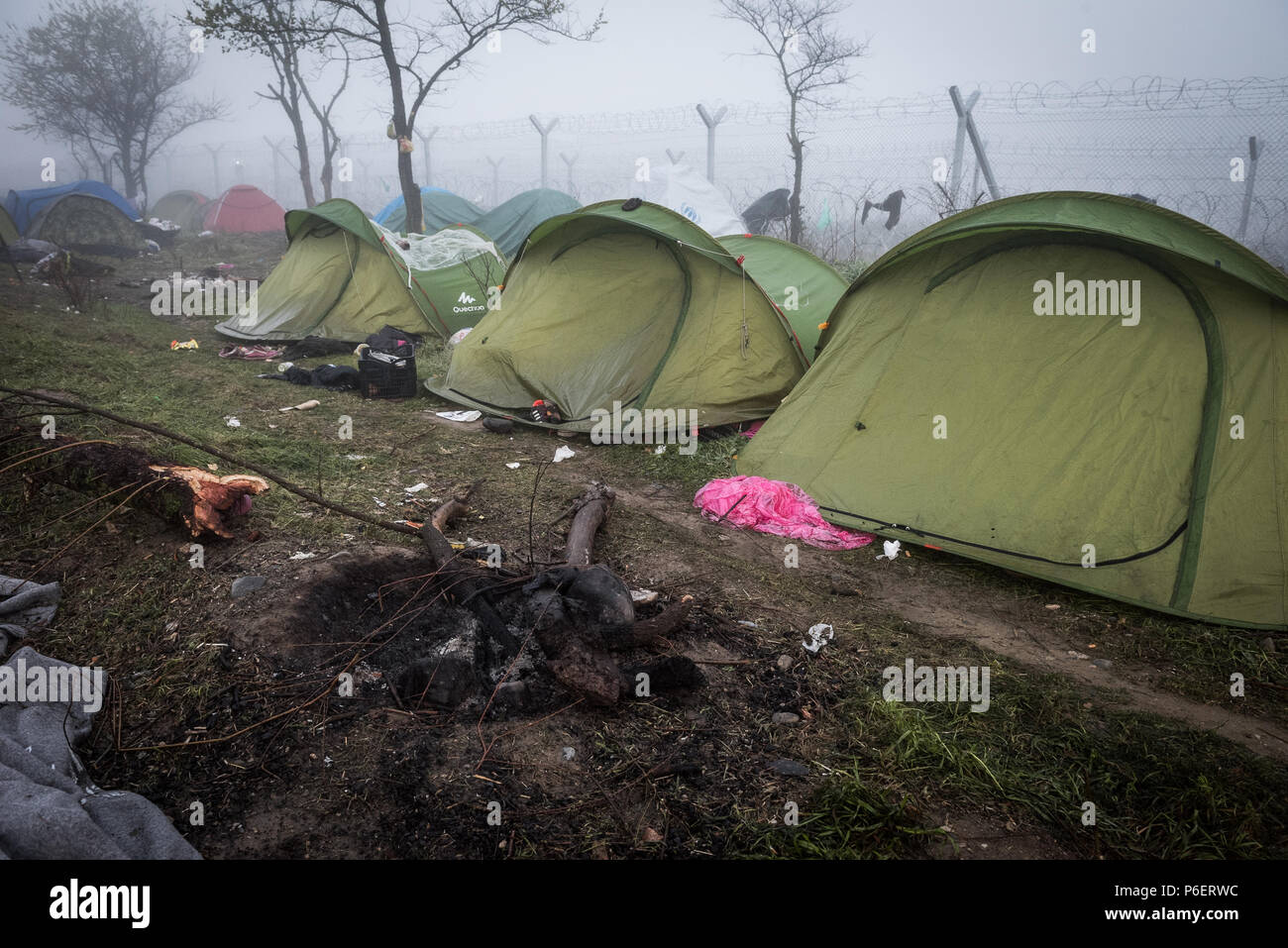 Une tente et plusieurs vêtements accrocher sur une clôture en fil barbelé à la limite du camp de réfugiés de fortune de l'Greek-Macedonian frontière près du village grec de J Banque D'Images