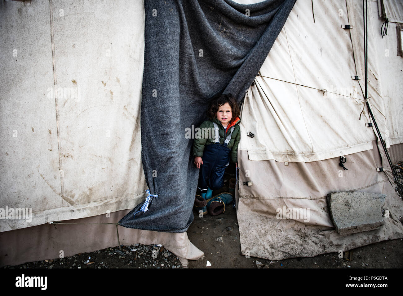 Fille de réfugiés est debout à l'extérieur de sa tente au camp de fortune du Greek-Macedonian frontière près du village grec de Idomeni. Banque D'Images