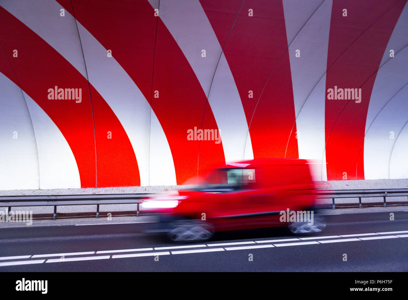 Une voiture rouge conduite rapide dans un tunnel avec rayures rouge sur le mur dynamique. Banque D'Images