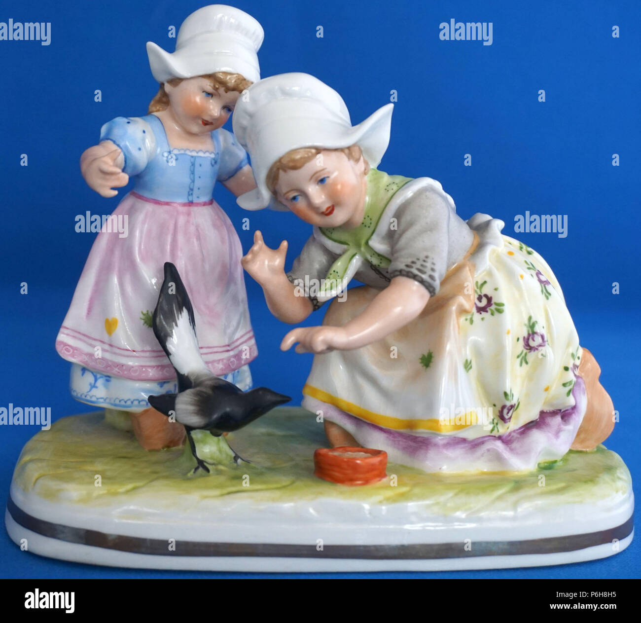 Vintage Figurine porcelaine allemande Figure ou les enfants néerlandais en costume national nourrir un oiseau pie Banque D'Images