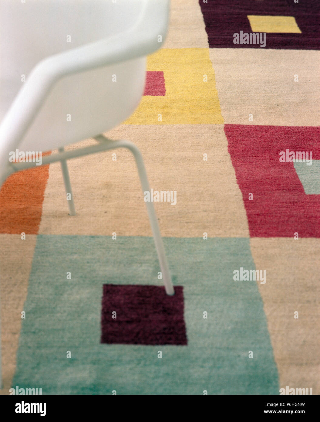 Close-up d'une chaise de style années 50 blanc sur tapis en laine coloré vérifié Banque D'Images