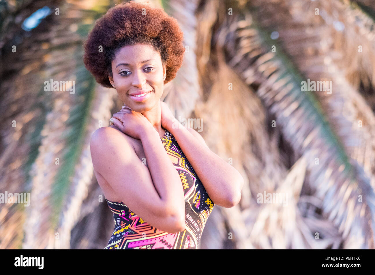 Cute smiling afro africaine fille modèle poser dans un endroit tropical. l'heure d'été et l'activité de loisirs pour la belle jeune femme souriant sous le soleil avec Banque D'Images