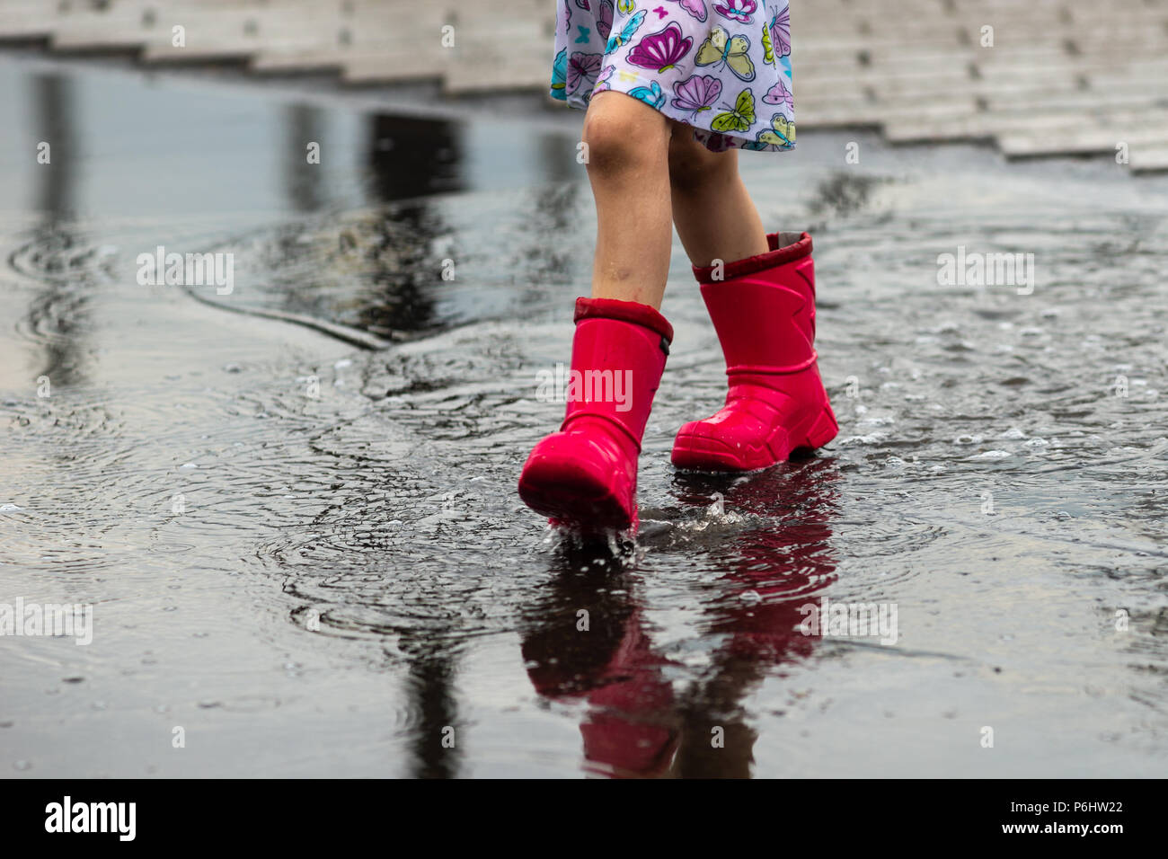 Météo russe, Moscou. Samedi, 30 juin, 2018. Les jambes d'une jeune fille non identifiée, méconnaissable en rouge des bottes de pluie. La fille va à travers la flaque. Banque D'Images