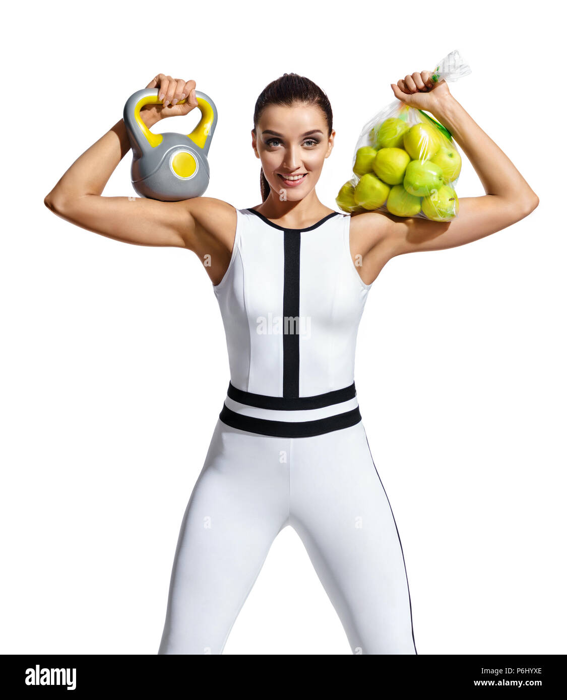 Happy sporty woman avec kettlebell et sac de pommes. Photo de mode dans le sportswear femme musclée sur fond blanc. Style de vie sain et mot Banque D'Images