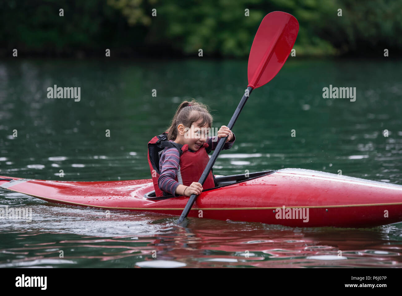 Les jeunes adolescentes gère activement un kayak sports voile sur une belle rivière Banque D'Images