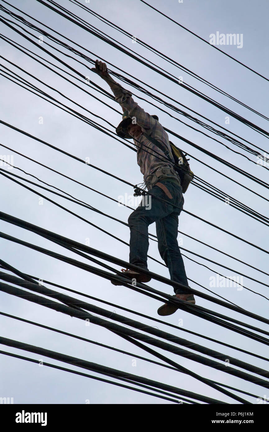 L'alimentation et les câbles de téléphone Thaïlande vivent dans la vue de la communauté. Trois hommes sont considérés ici marcher le long de ces lignes de 'pouvoir' au crépuscule Banque D'Images