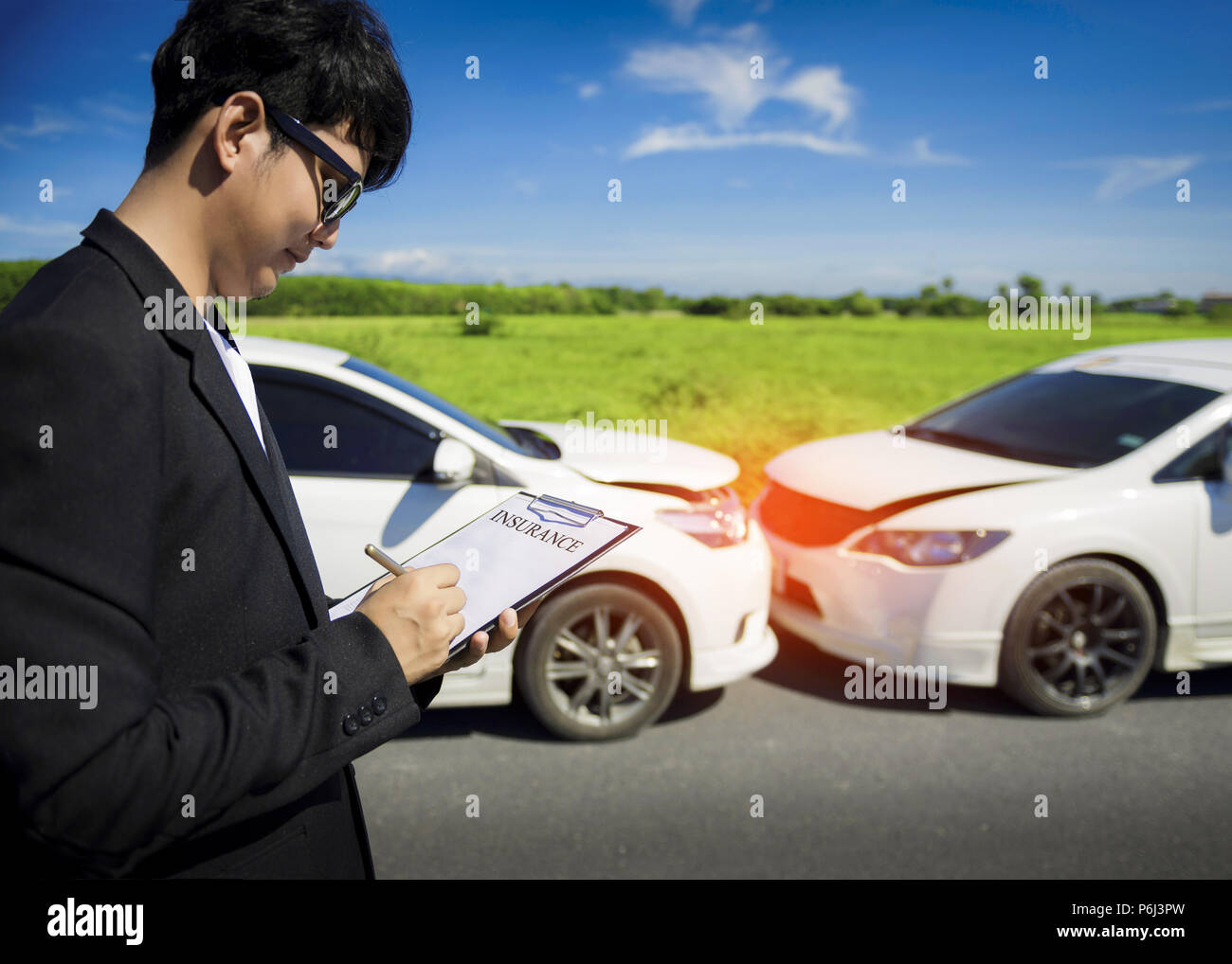 Agent d'assurance, writing on clipboard après accident de voitures. Banque D'Images