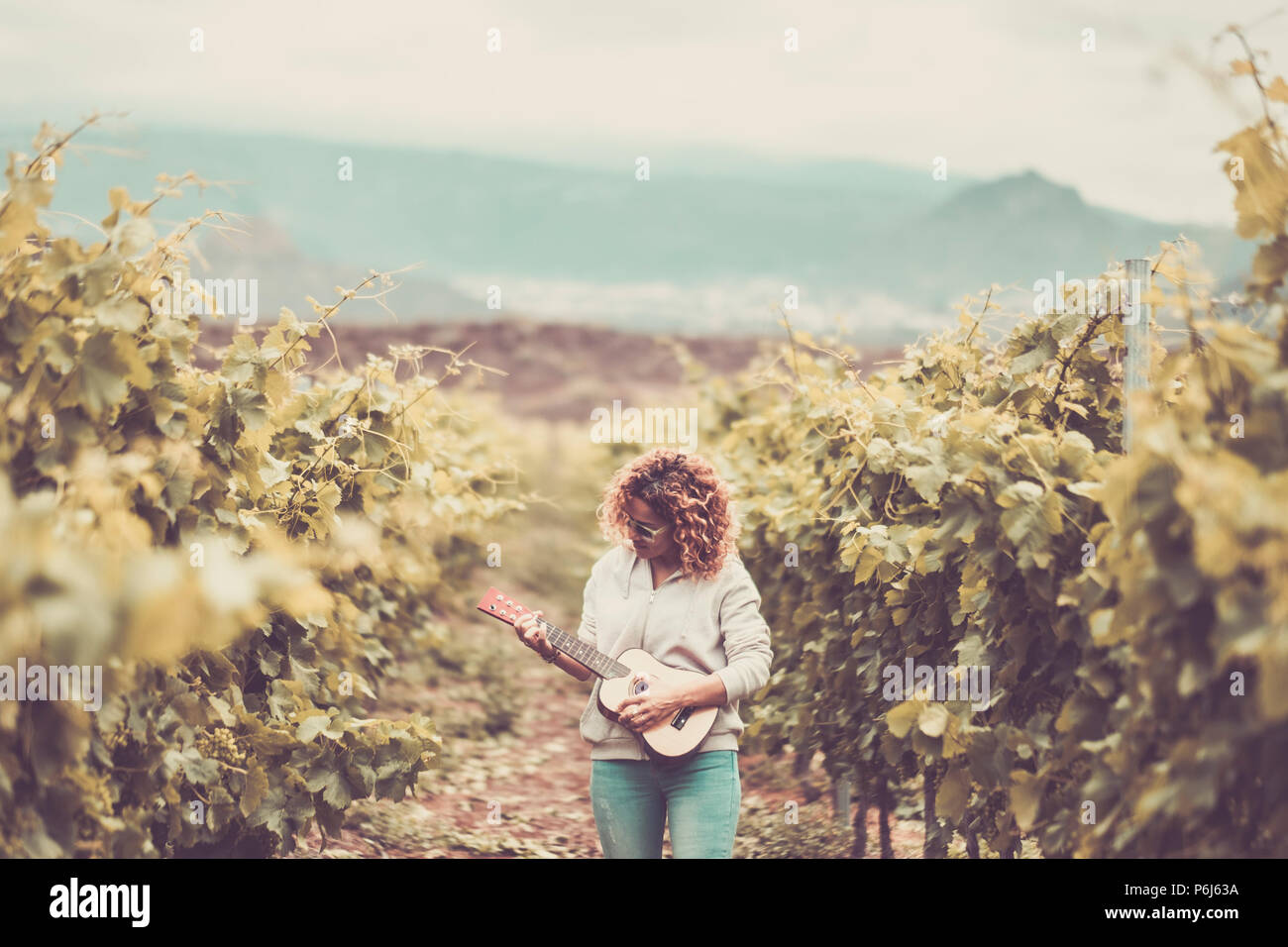 Belle belle femme de race blanche se promener seul dans la vigne fond vert chanter un ukulele guitare acoustique. liberté style hippy con Banque D'Images Belle belle femme de race blanche se promener seul dans la vigne fond vert chanter un ukulele guitare acoustique. liberté style hippy con Banque D'Images