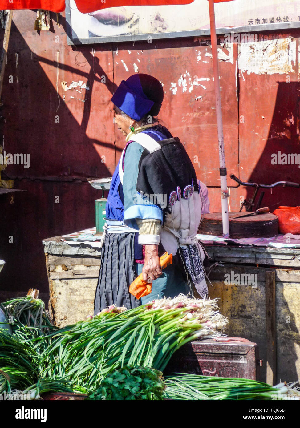 Lijiang, Chine - Avril 2015 : femme mariée de la minorité Naxi chinois portant des vêtements traditionnels alors que l'achat de nourriture au marché local Banque D'Images