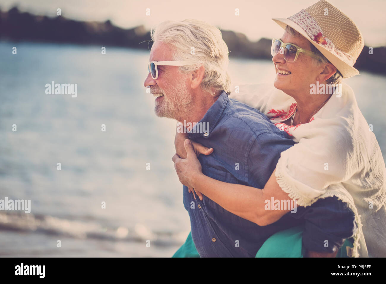 Happy senior couple s'amuser et profiter de l'activité de loisirs de plein air sur la plage. l'homme porter la femme sur le dos pour profiter ensemble un ancien lifestyl Banque D'Images