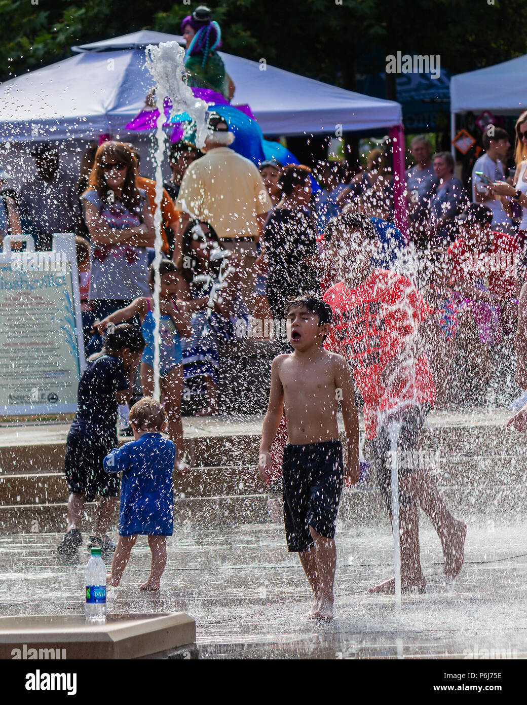 Un garçon hurle en voyant l'eau froide dans les fontaines de Splashville au centre-ville de Asheville, NC, USA Banque D'Images