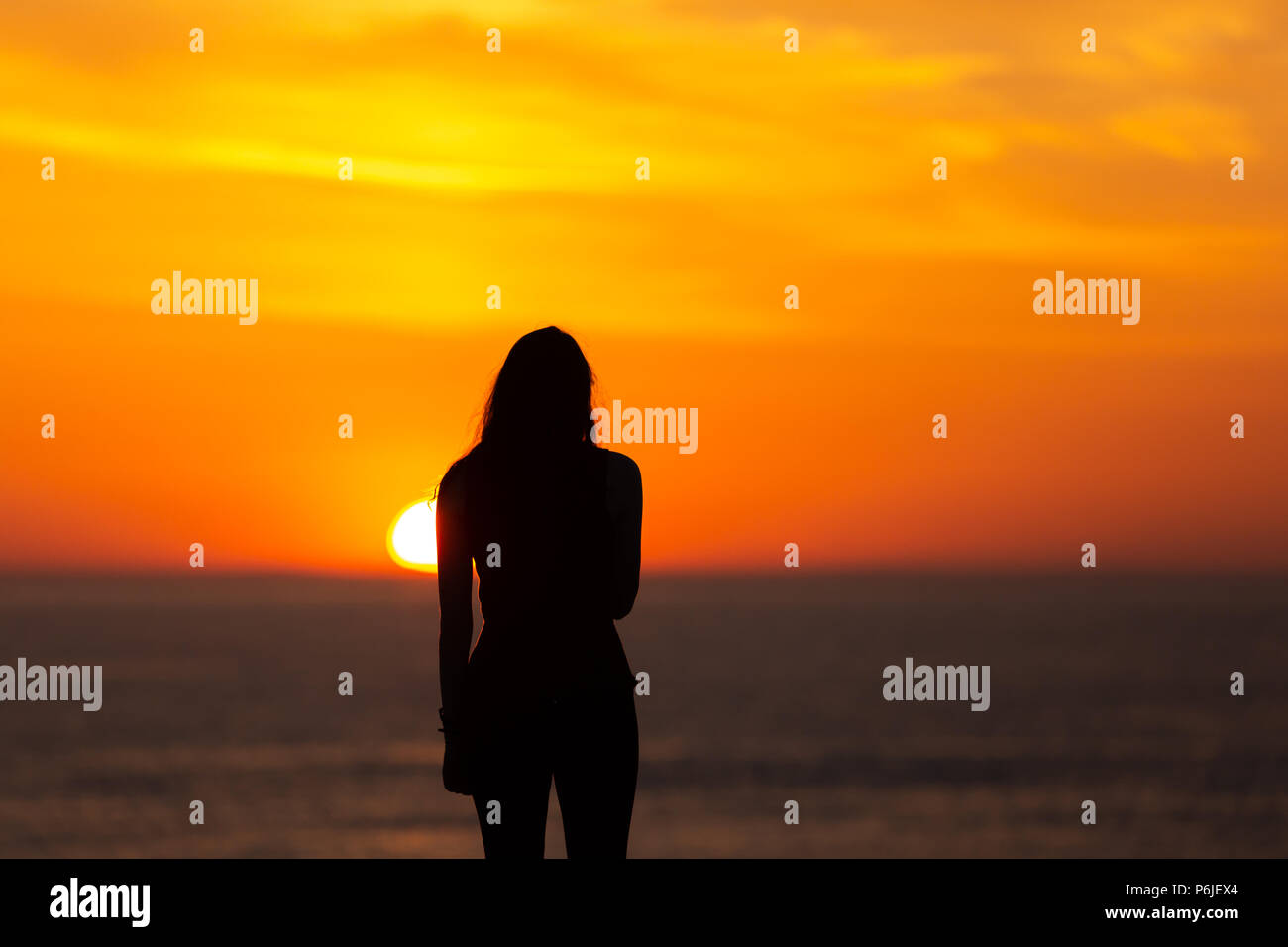 Une jeune fille se découpé sur une orange coucher de soleil sur la côte ouest d'Aberystwyth après un autre jour ensoleillé chaud. © Ian Jones/Alamy Live News. Banque D'Images