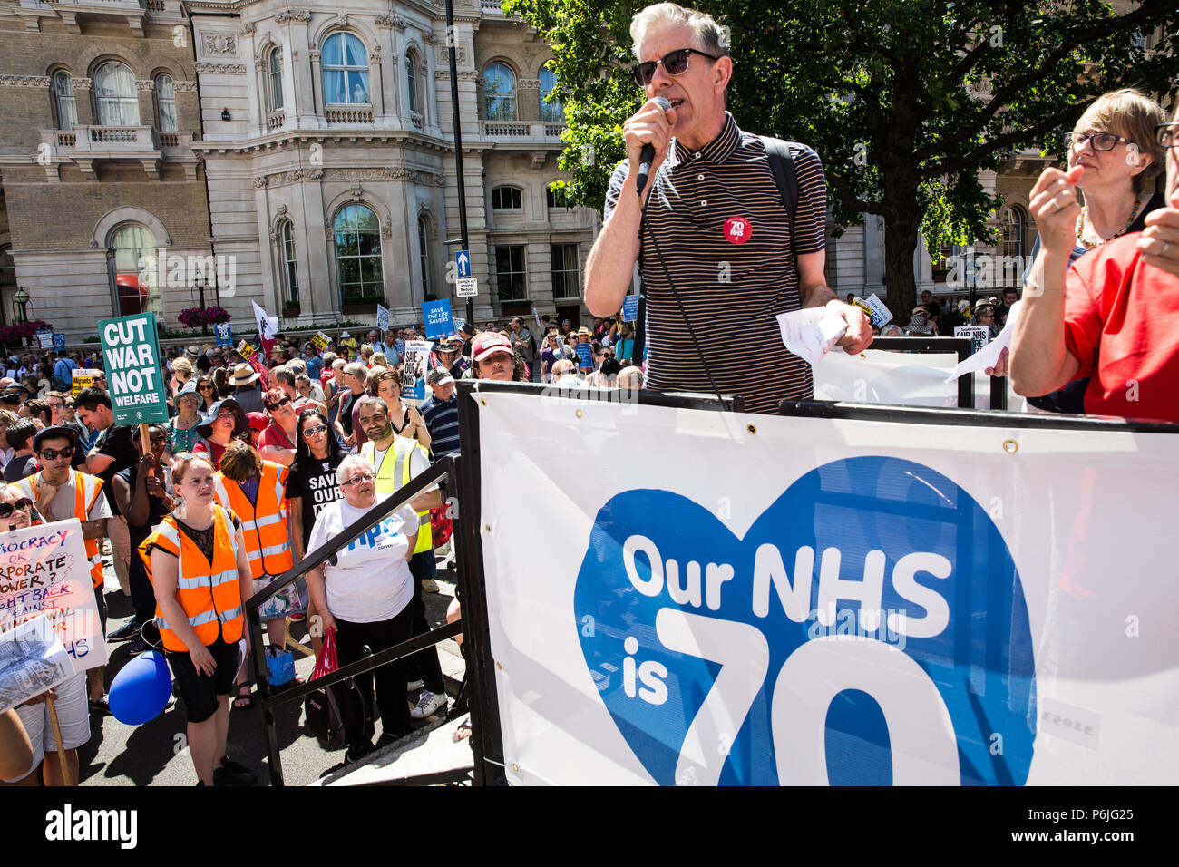 Londres, Royaume-Uni. 30 juin 2018. Chris Nineham de Coalition contre la guerre et l'arrêt des adresses d'atout des milliers de personnes, y compris un grand nombre d'infirmières, de médecins et d'agents de santé, la participation à une manifestation et une marche pour marquer le 70e anniversaire de la National Health Service (NHS) et pour exiger la fin de coupures à et la privatisation des services publics. L'événement était organisé par l'Assemblée du peuple contre l'austérité, campagnes de santé ensemble, le TUC et onze autres syndicats de la santé. Credit : Mark Kerrison/Alamy Live News Banque D'Images