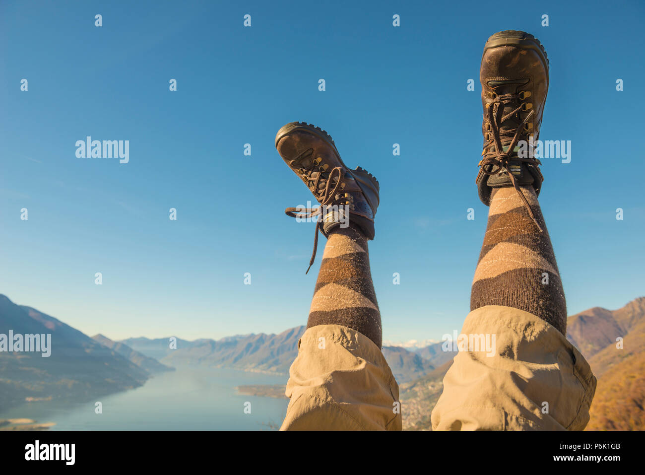 Des chaussures de randonnée et les jambes en l'air sur la chaîne de montagnes des Alpes et du Lac Majeur au Tessin, Suisse. Banque D'Images