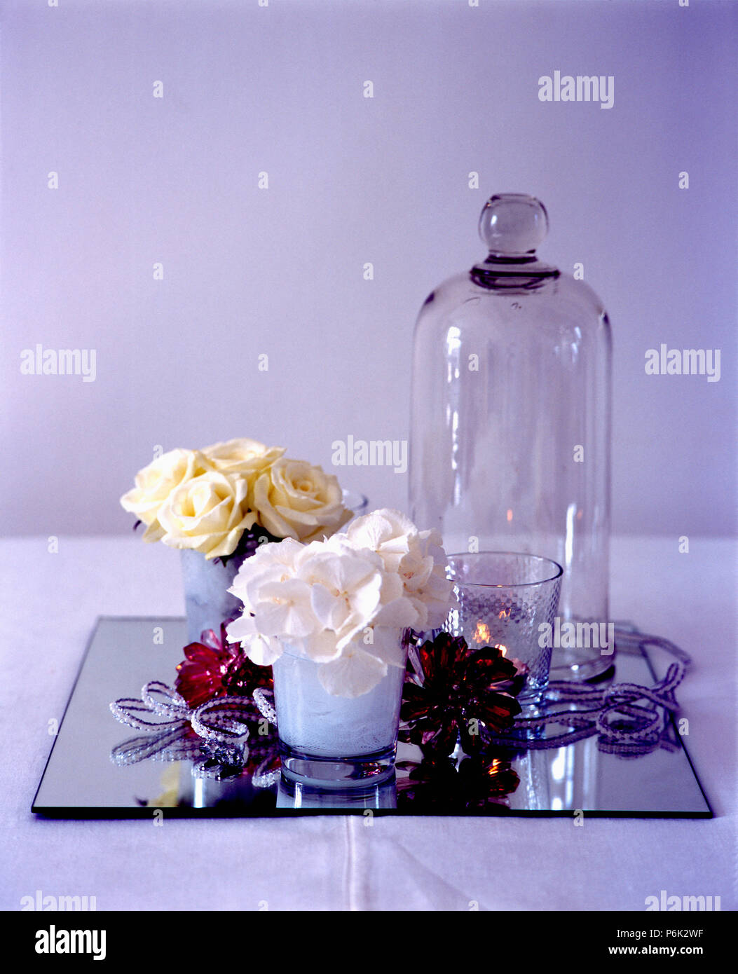 Still-Life de petits vases de roses crème à côté de grand dôme en verre sur verre Banque D'Images