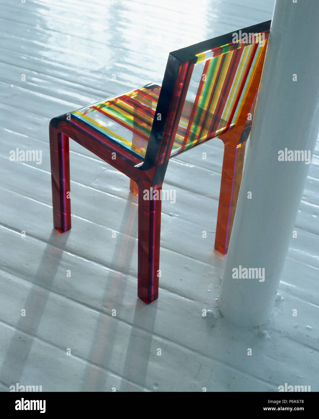 Close-up de perspex à rayures de couleur chaise sur un parquet blanc Banque D'Images